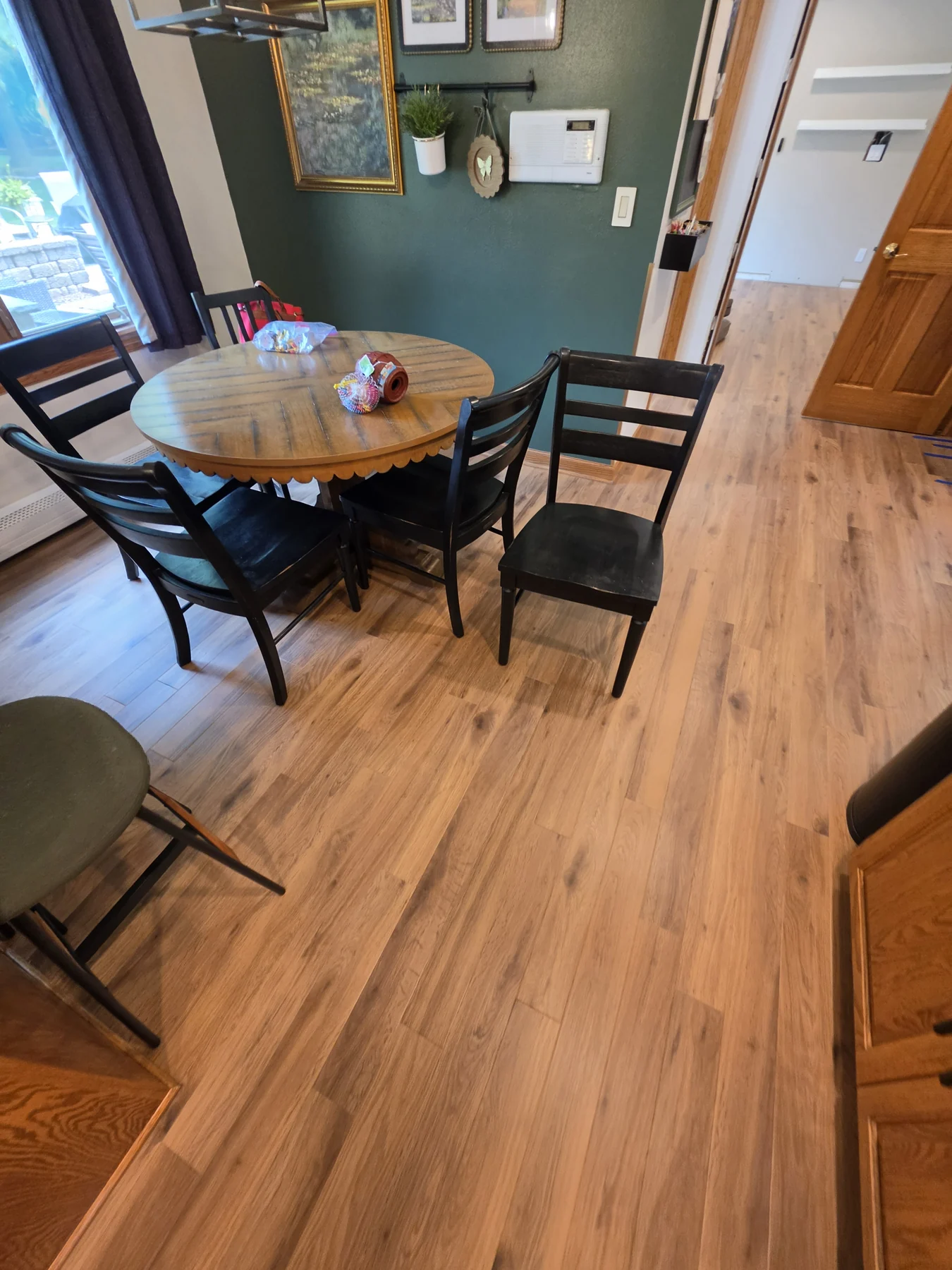 Warm-toned flooring beside a round dining table and dark chairs