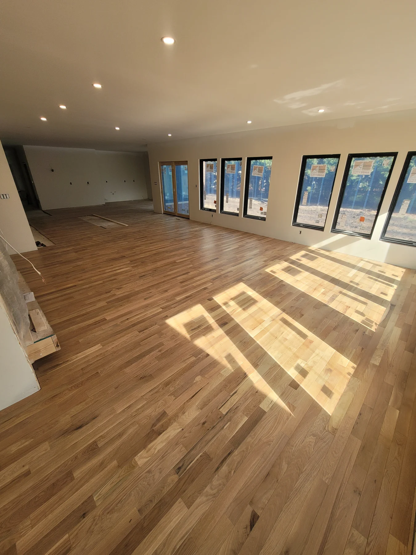 Installed hardwood across a sunlit great room on an active construction site