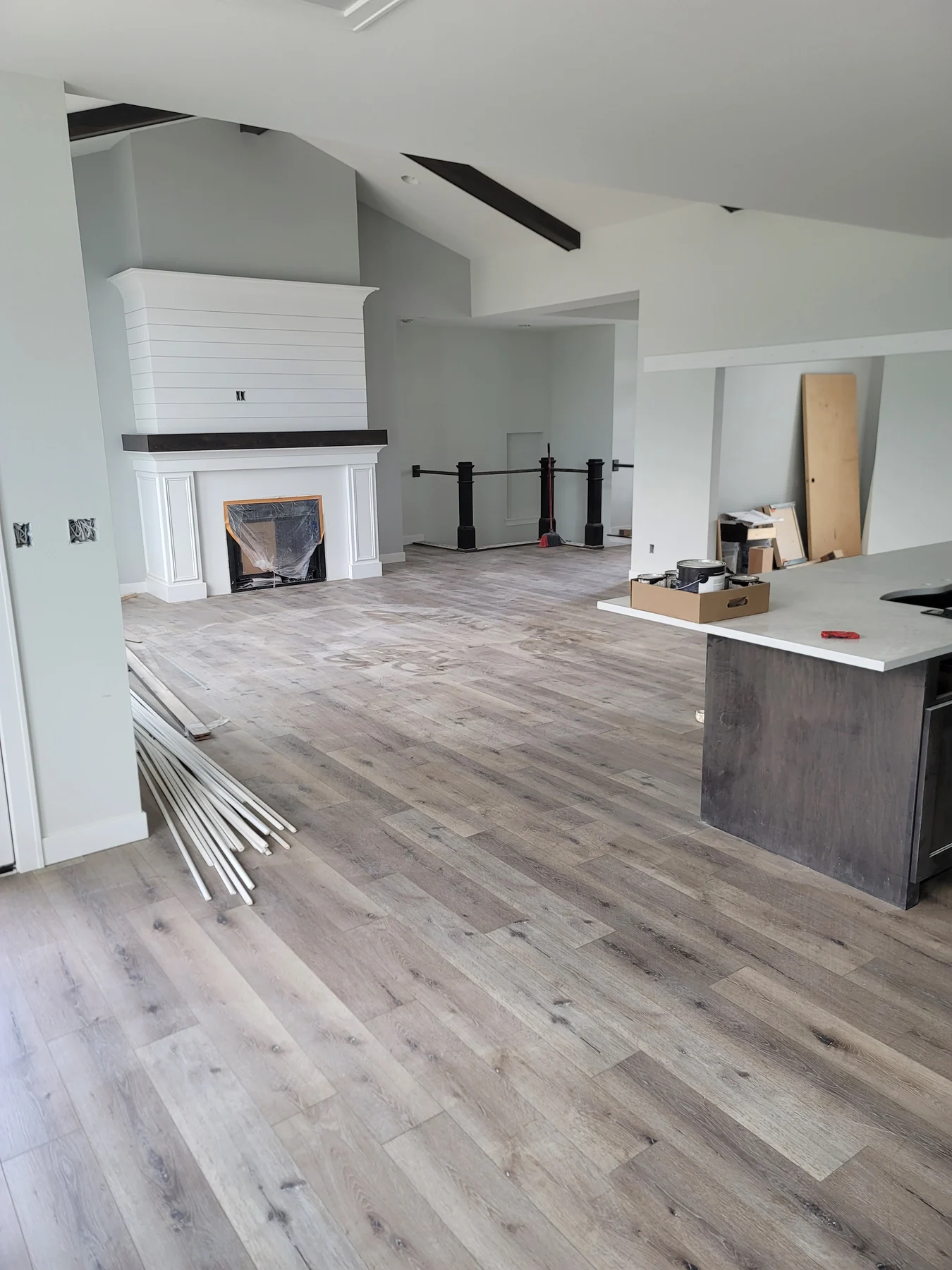 Gray laminate flooring across an open living area with a white fireplace and kitchen island