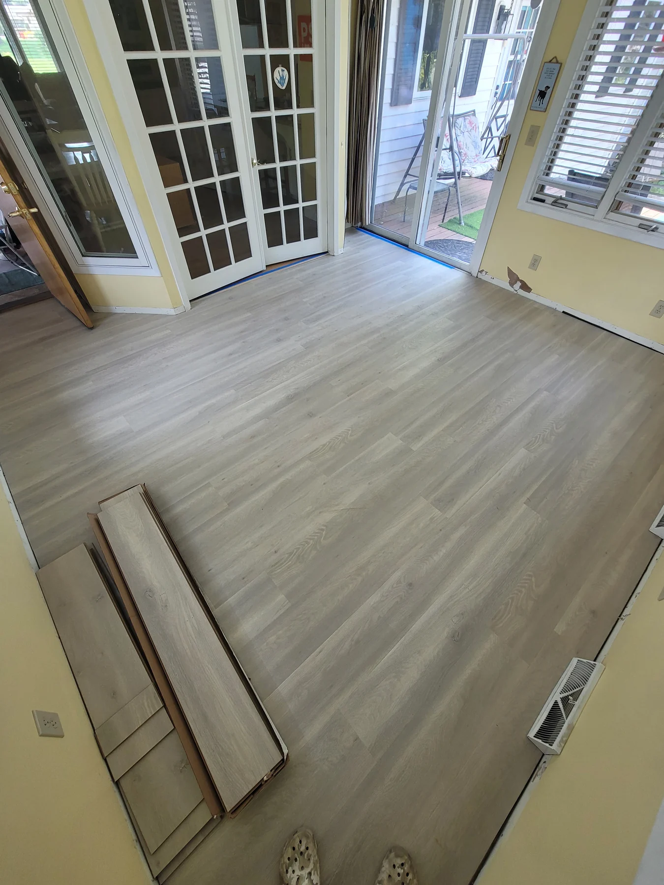 Light laminate flooring in a sunroom with glazed doors and windows