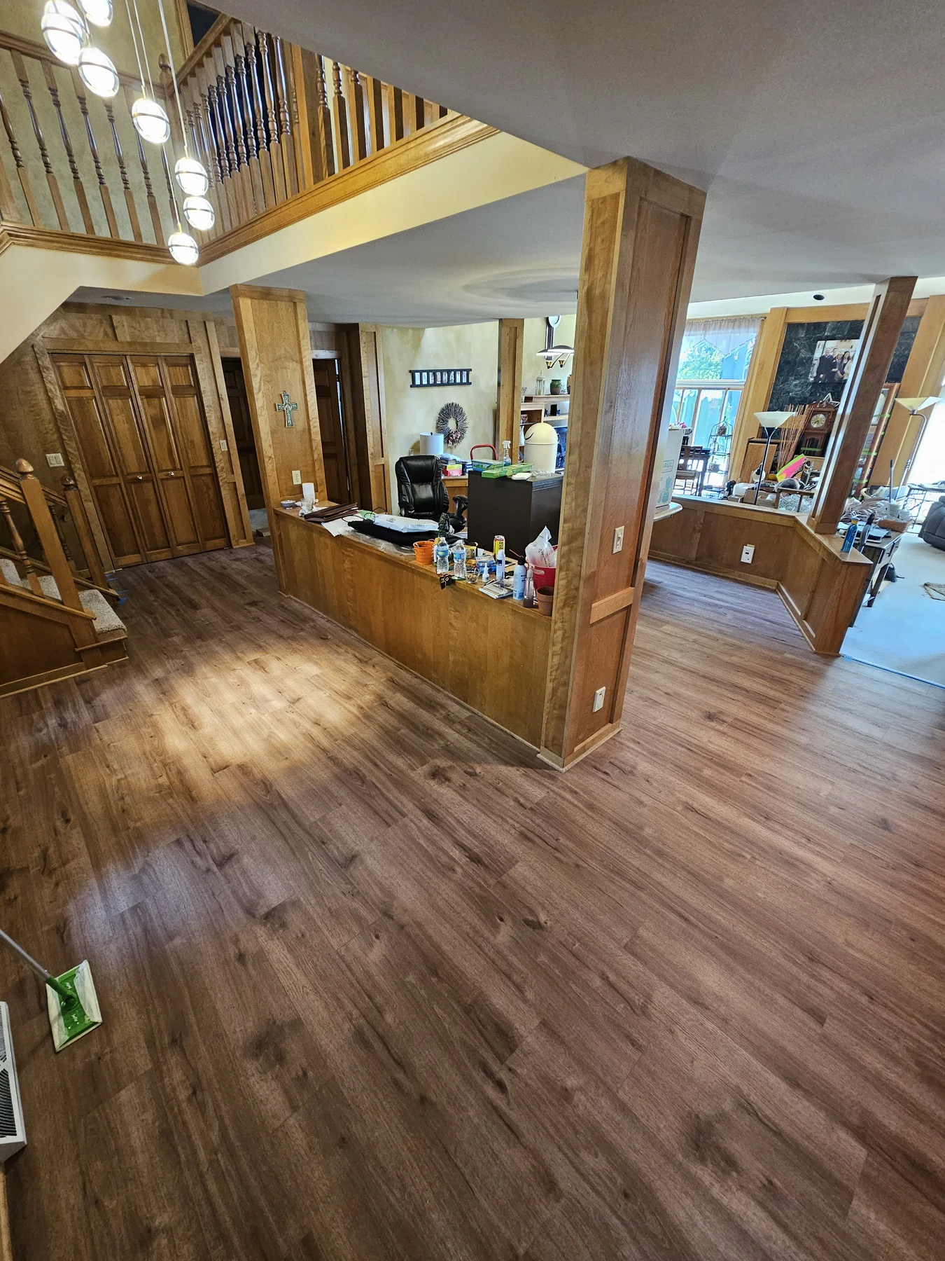 Brown luxury vinyl plank flooring through a wood-trimmed entry and living area