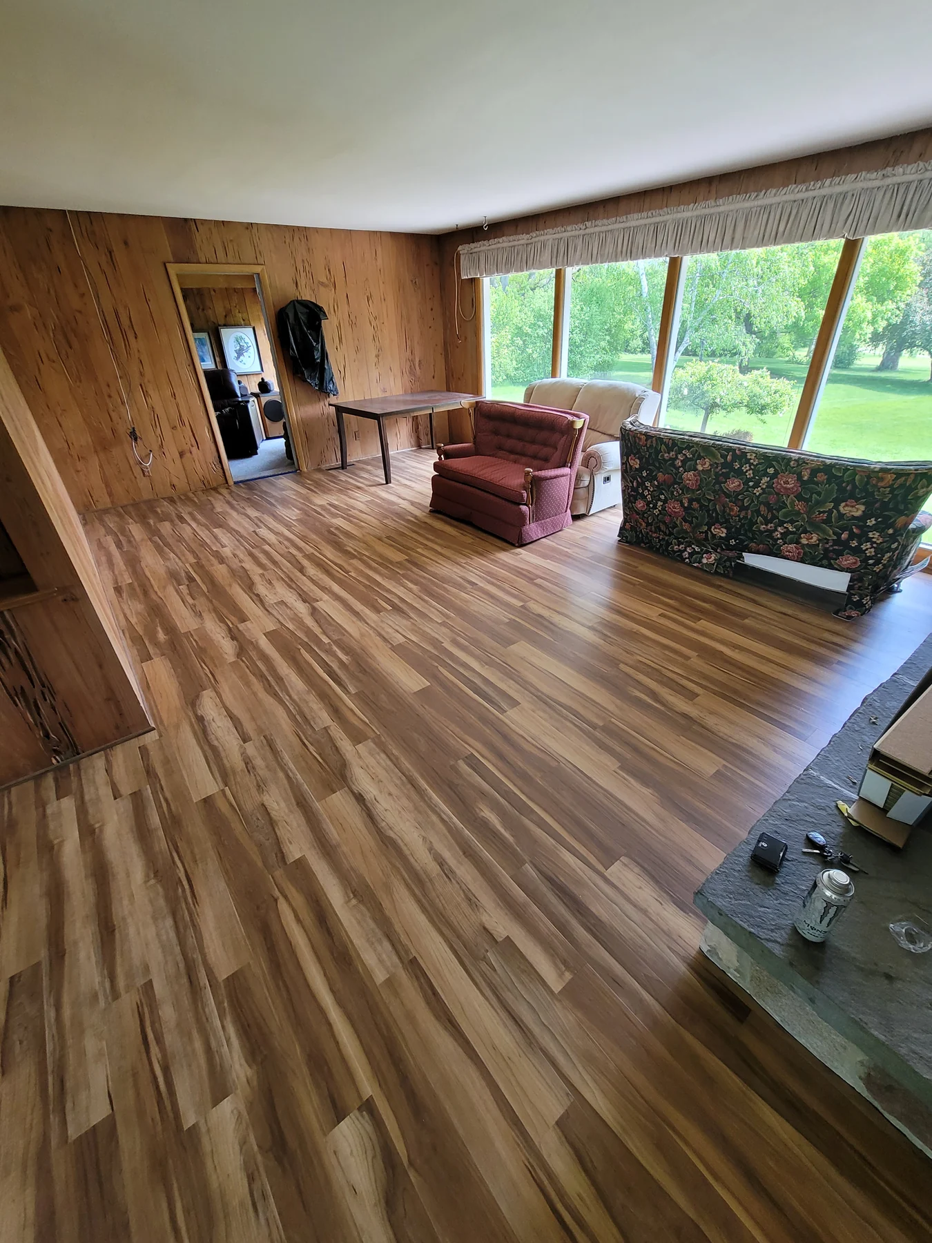 Brown luxury vinyl plank flooring through a wood-paneled living room