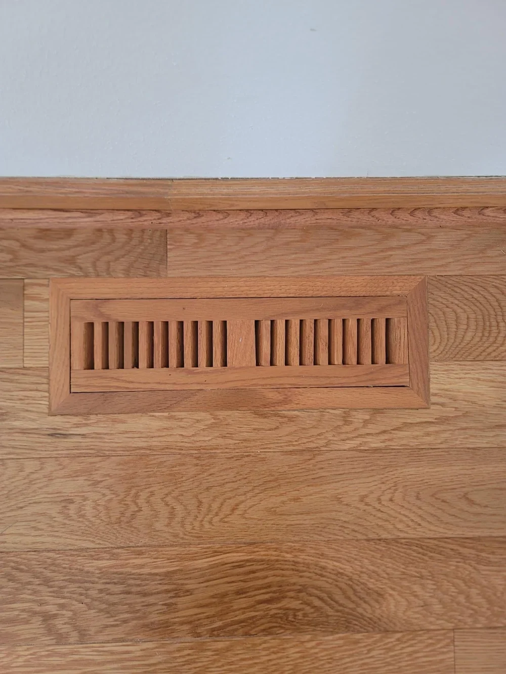 A wood floor vent fitted flush within a wood floor