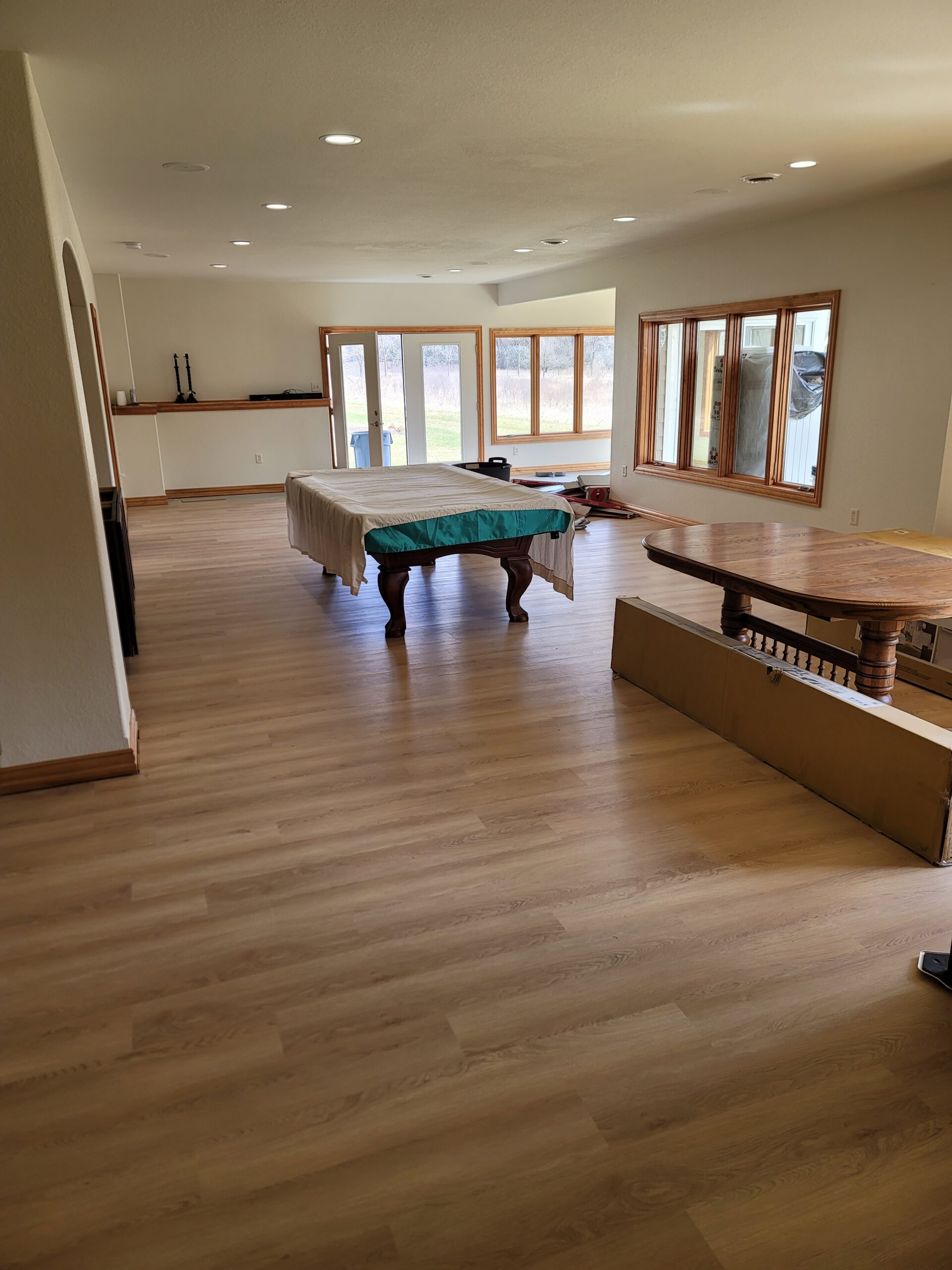 Luxury vinyl plank flooring across a bright recreation room with a pool table and large windows
